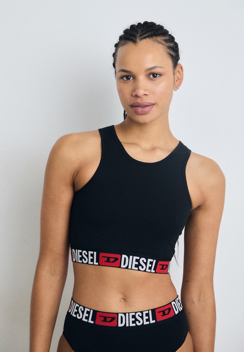 Černá sportovní podprsenka a vysoké kalhotky s bílým a červeným logem "DIESEL" na pásku. Hladká tkanina s přiléhavým střihem bez dalších doplňků.