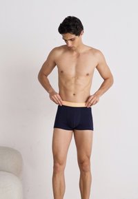 Marineblaue Boxershorts aus elastischem Stoff mit einem leichten, orangenen Markenlogo, aus glattem, dehnbarem Material und mit taillierter Passform.