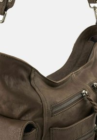 Borsa a spalla in pelle marrone con molte tasche con zip, texture liscia e dettagli cuciti. Presenta un'apertura ampia e curvata.