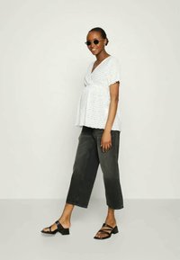 White eyelet blouse with short puff sleeves, paired with dark cropped jeans and black heeled sandals. Accessories include round sunglasses.