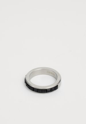 Silver metal ring with black square stones embedded around the band and "GUESS" engraved inside the ring.