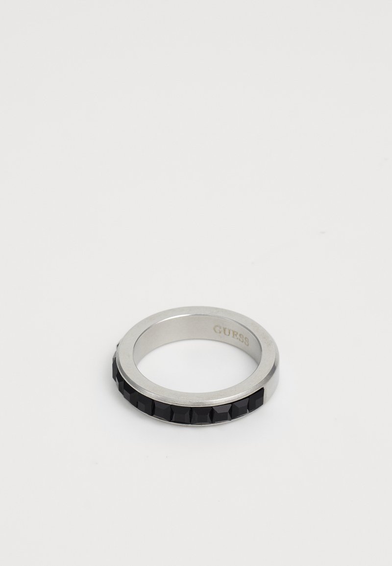 Silver metal ring with black square stones embedded around the band and "GUESS" engraved inside the ring.