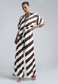 Brown and white striped two-piece outfit featuring a relaxed button-up shirt and wide-leg pants with an elastic waist and slits at the hem.
