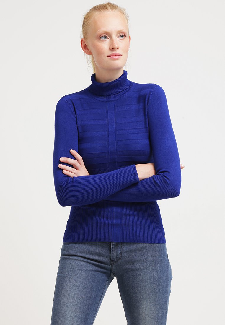 Pullover mit Rollkragen aus kräftigem Blau, mit strukturiertem Paneldesign und geripptem Stoff für eine figurbetonte Passform. Trägt man mit Jeans.
