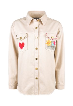 Beige button-up jacket with long sleeves, two chest pockets decorated with studs, a red heart patch, and colorful flower and star patches.