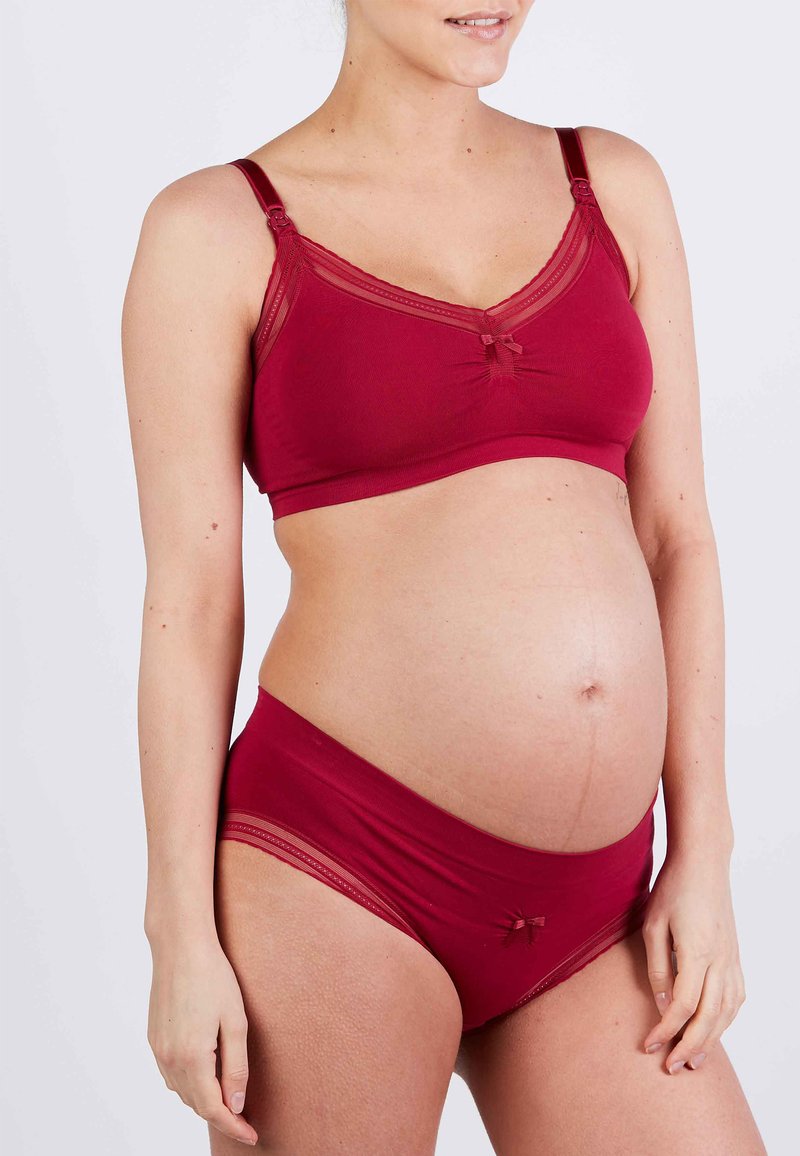 Zwangere beha en slipset in diep rood. Zachte stof met doorschijnende kanten accenten, strikdetails en een comfortabele rekbare pasvorm voor zwangere lichamen.