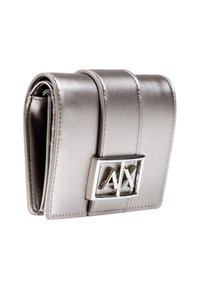 Portafoglio argento metallizzato con texture liscia, caratterizzato da un design pieghevole e un cinturino con logo argentato come dettaglio distintivo.