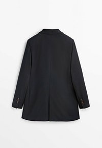 Blazer noir à coupe cintrée, fente unique à l'arrière, et poignets à trois boutons. Confectionné dans un tissu lisse et structuré.