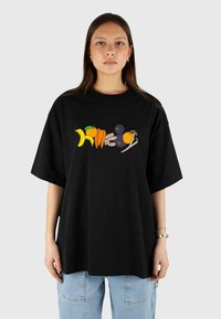 Czarna, oversize t-shirt wykonana z bawełny, z kolorowym nadrukiem owoców i warzyw z przodu. Krótkie rękawy oraz okrągły dekolt.