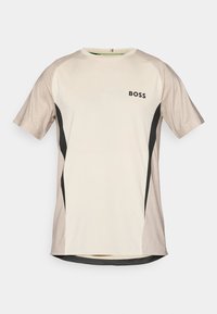 Rövid ujjú krém színű sportpóló bézs ujjal, fekete oldalsó panelekkel és a bal mellen található "BOSS" logóval.
