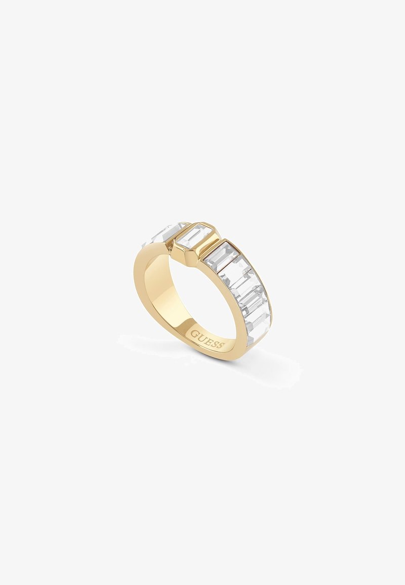 Bague anneau en or avec des pierres précieuses rectangulaires transparentes sur le dessus, gravée du nom de la marque Guess à l'intérieur de l'anneau.