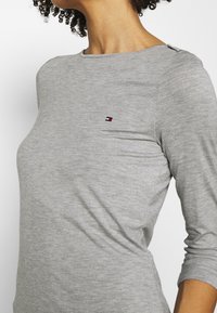 Grijze langslavige t-shirt gemaakt van zachte stof, met een ronde halslijn en een klein logo op de borst. Subtiele stiksels.