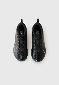 Scarpe da ginnastica nere con una texture lucida, dettagli verdi e un design leggero. Presentano una chiusura con lacci e un'asola per facilitare l'indossamento.