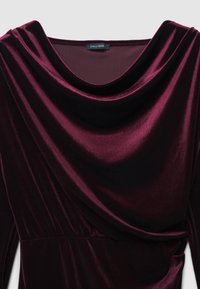 Bordeaux-farbenes Samtkleid mit drapiertem Ausschnitt und weicher Textur, einer taillierten Taille und glattem Stoff, der Lichtreflexionen zeigt.
