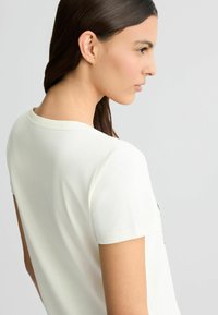 Lichtgekleurde korte mouwen T-shirt met ronde hals, gemaakt van zachte stof, met een gladde textuur en minimalistisch ontwerp.