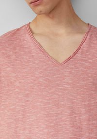 Lichtrood V-hals t-shirt van een zachte, gestructureerde stof met dunne, contrasterende afwerking. Het materiaal heeft een subtiel gestreept patroon.