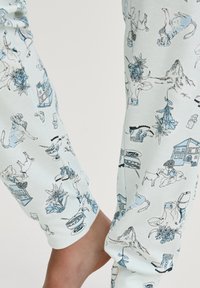 Lichtblauwe pyjamabroek met een herhaald patroon van dieren, huizen en bloemelementen. Zachte, rekbare stof met een comfortabele pasvorm.