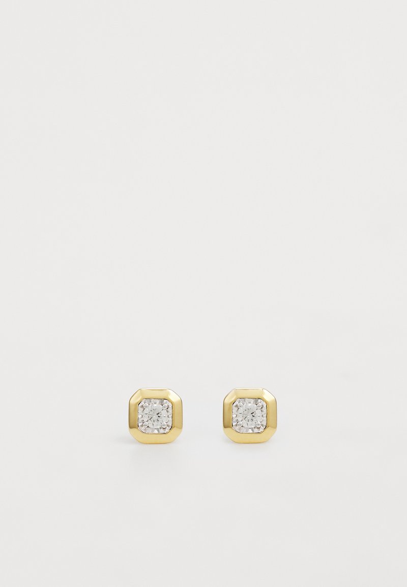 Guldtonede oktagonale studs med cubic zirconia centersten, der skaber et minimalistisk, geometrisk design.
