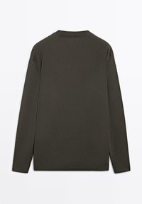 Dunkelgrünes Langarmshirt mit Rundhalsausschnitt, aus weichem Stoff gefertigt. Verfügt über einen geraden Schnitt und seitliche Schlitze für mehr Bewegungsfreiheit.