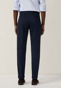 Pantaloni blu navy realizzati in tessuto di trama, con una vestibilità sartoriale, passanti per cintura e due tasche posteriori con chiusura a bottone.