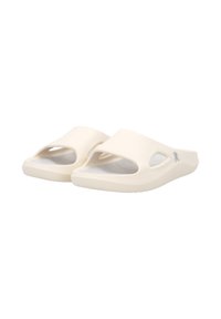 Cream-colored slide sandals made of flexible material, featuring open toes, cut-out sides, and a textured footbed for grip.