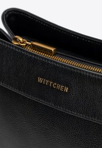 Czarna skórzana torba o teksturowanym wykończeniu, złotym zamku błyskawicznym i wytłoczonym logo "WITTCHEN" z przodu. Elegancki design z praktycznymi elementami.