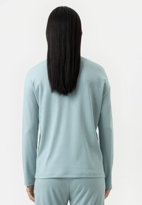 Haut à manches longues bleu clair avec une coupe décontractée, un col rond et un tissu doux. Dispose d'une texture lisse et d'un design simple.