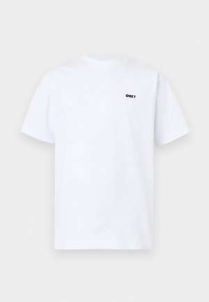 Λευκό μπλουζάκι με κοντά μανίκια και στρογγυλή λαιμόκοψη, με μικρό μαύρο κείμενο "OBEY" στο αριστερό στήθος, πάνω σε απλό φόντο.