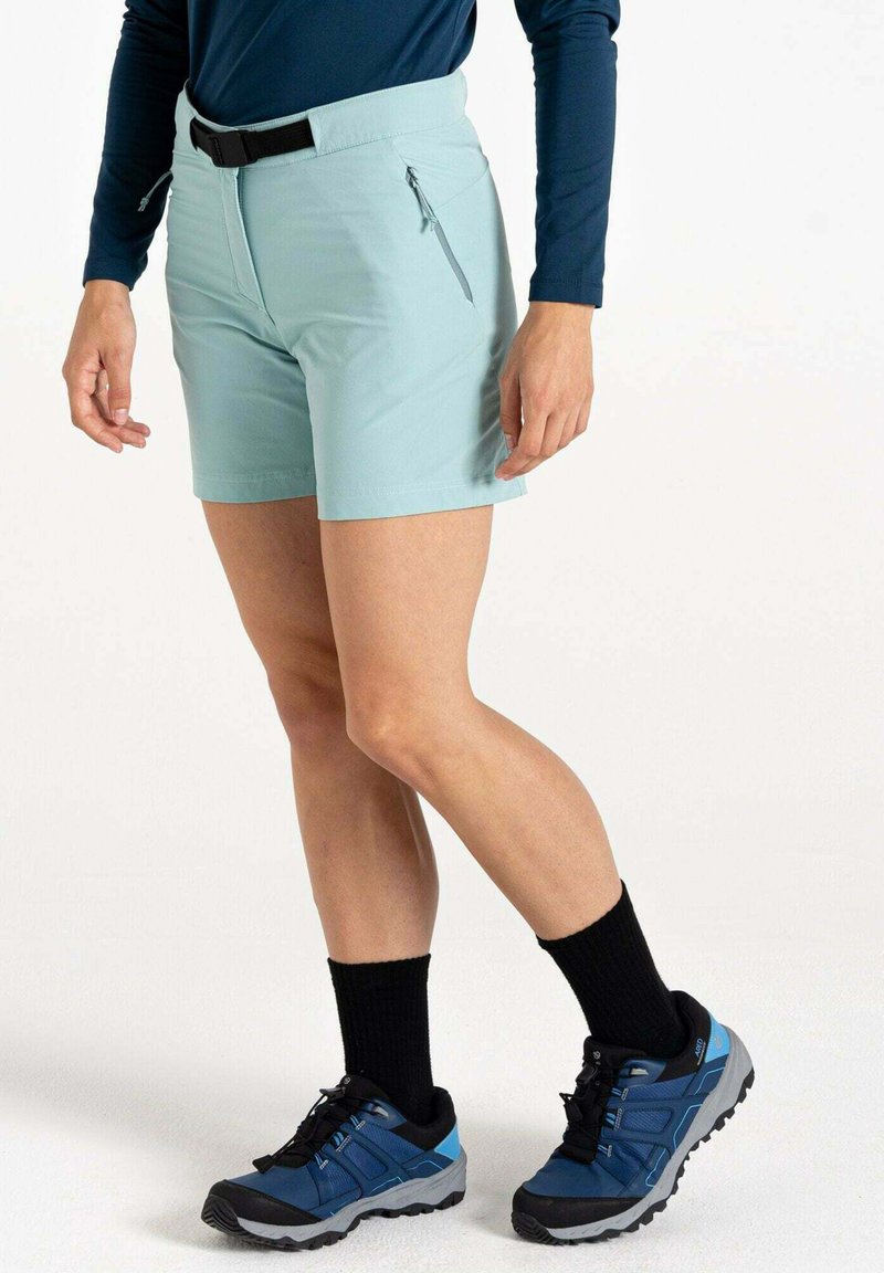 Hellblaue Shorts mit flachem Bund und einer Reißverschlusstasche, kombiniert mit schwarzen Knöchelsocken und blauen und schwarzen Wanderschuhen.