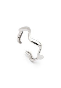 Pulsera de muñeca de metal plateado con un diseño ondulado y escultórico. Acabado suave con extremos abiertos, presentando curvas sutiles y variaciones en el grosor.