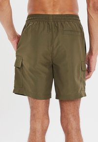 Pantaloni cargo verde oliva con cintura elastica. Presentano tasche laterali a patta e una tasca posteriore applicata. Tessuto liscio e leggero.