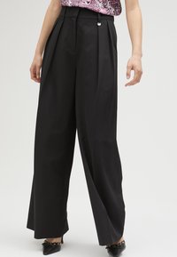 Zwarte wijde pantalons met plooien, gemaakt van een soepele stof, hoog in de taille en met metallic hardwareaccent bij de tailleband.