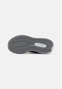 Suela de sneaker de goma gris con patrones de tracción texturizados. Bordes suaves y redondeados con un acento blanco en el talón.