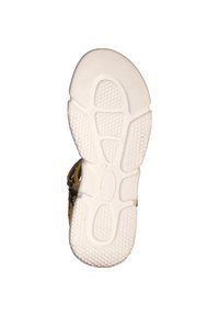 Shoe sole featuring a white rubber material with textured patterns for grip, with a tan upper visible at the edge, showing a strap design.