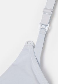 Gaiši zils krūšturis ar mīkstu audumu, regulējamām siksnām un plastikāta piederumiem. Ir gluda tekstūra un bezšuvju dizains.