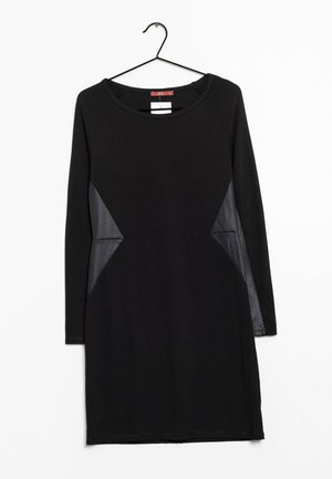 Schwarzes Langarmkleid mit rundem Ausschnitt, das seitliche transparente schwarze Einsätze aufweist. Glattes Material und enganliegendes Design.