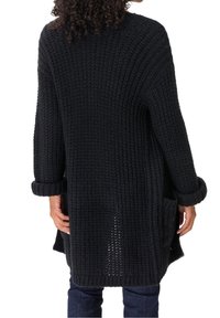Schwarze Strickjacke mit lockerer Passform, geripptem Muster, langen Ärmeln, umgeschlagenen Manschetten und seitlichen Taschen. Die Rückansicht zeigt ein offenes Webdesign.