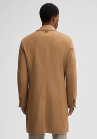 Tan wollen jas met enkele split, notch revers en dichte manchetten, met een gladde textuur en minimale details aan de achterkant.