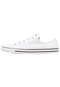 White canvas sneaker with round toe, rubber sole, black stripe accents, and six eyelet lace-up design. Smooth texture, low-profile silhouette.