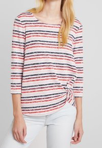 Gestreiftes Langarmshirt in Weiß, Rot und Marineblau. Weicher Stoff mit einem Knoten-Detail an der Seite, Rundhalsausschnitt und Dreiviertelärmeln.