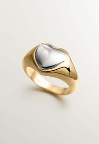 Anillo de oro con una parte superior metálica plateada en forma de corazón. Superficie lisa con un brillo pulido, bordes curvados y una banda ancha.