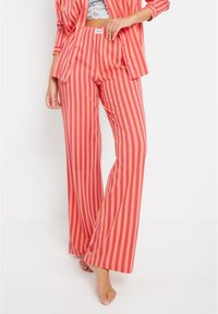 Pajama set s prugama u ružičastoj i breskvastoj boji koji se sastoji od košulje sa dugmadima i širokih hlača. Mekan materijal s opuštenim krojem i elastičnim pojasom.