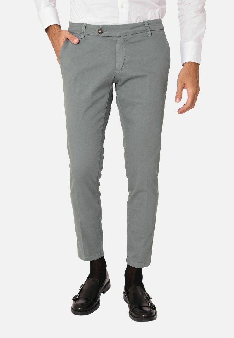 Chinos grigi chiari con una vestibilità slim, dotati di chiusura con bottone, tasche laterali e orli cuciti. Abbinati a mocassini neri e calzini.
