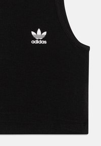 Μαύρο ριγωτό αμάνικο τοπ με λευκό λογότυπο της Adidas στο κέντρο. Αμάνικο σχέδιο με στρογγυλή λαιμόκοψη και ραμμένο στρίφωμα.