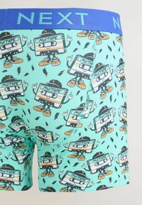 Pánské boxerky s tyrkysovým základem. Mají hravý vzor kazetové pásky, modrý elastický pas a strečový materiál.