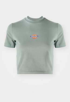 Chemise courte à manches courtes en coton vert atténué. Elle présente un col rond et un logo "Dickies" coloré sur la poitrine.