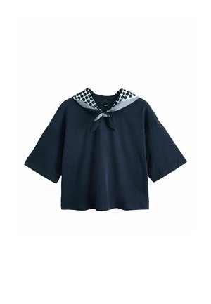 Cămașă albastru închis cu mânecă scurtă, mâneci largi și un fular cu buline alb-negru legat la gât.