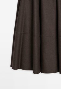 Gonna marrone lunga fino al ginocchio realizzata in tessuto testurizzato; presenta un design svasato con dettagli delle cuciture per una forma migliore.