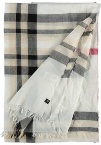 Manta de algodón con un gran patrón de cuadros en beige, negro y gris, con bordes deshilachados y una pequeña etiqueta negra en una esquina.