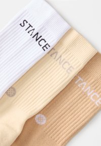 Három pár zokni fehér, világos bézs és barna színben. Mindegyik bordás textúrájú, és a "STANCE" logója kontrasztos színekben szerepel.